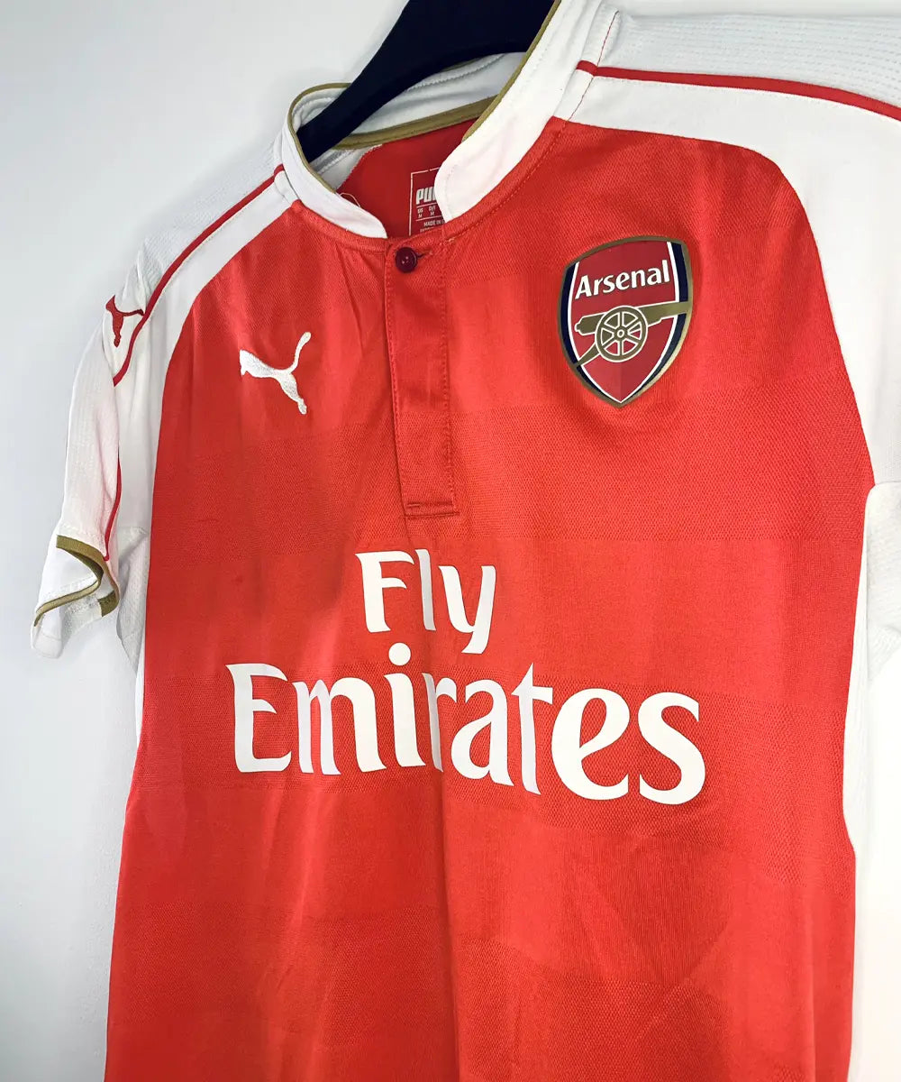 Maillot domicile vintage rouge et blanc d'Arsenal de la saison 2015-2016. On peut retrouver l'équipementier Puma et le sponsor fly emirates