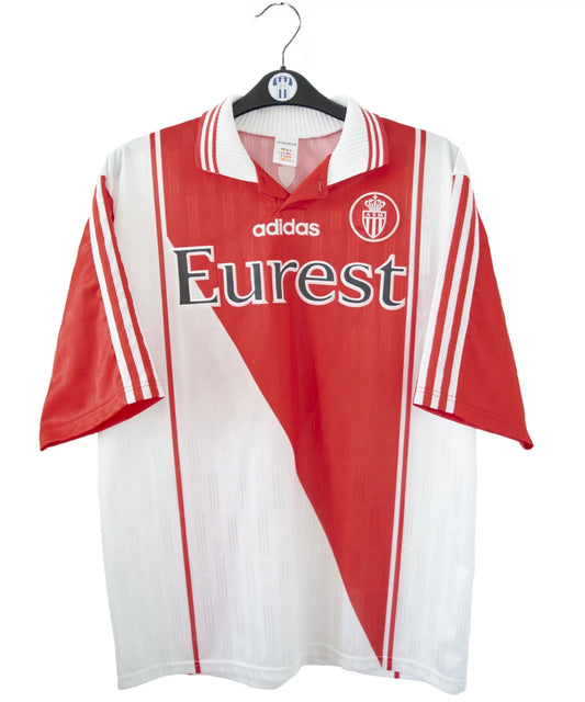 Maillot de foot vintage domicile rouge et blanc de l'AS Monaco de la saison 1996/1998. On peut retrouver l'équipementier adidas et le sponsor Eurest. Il s'agit d'un maillot authentique