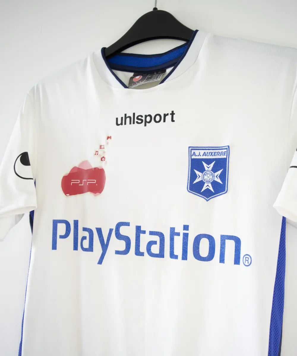 Maillot domicile de l'AJ Auxerre de couleur blanc et bleu. On peut retrouver l'équipementier uhlsport et les sponsors PSP et Playstation