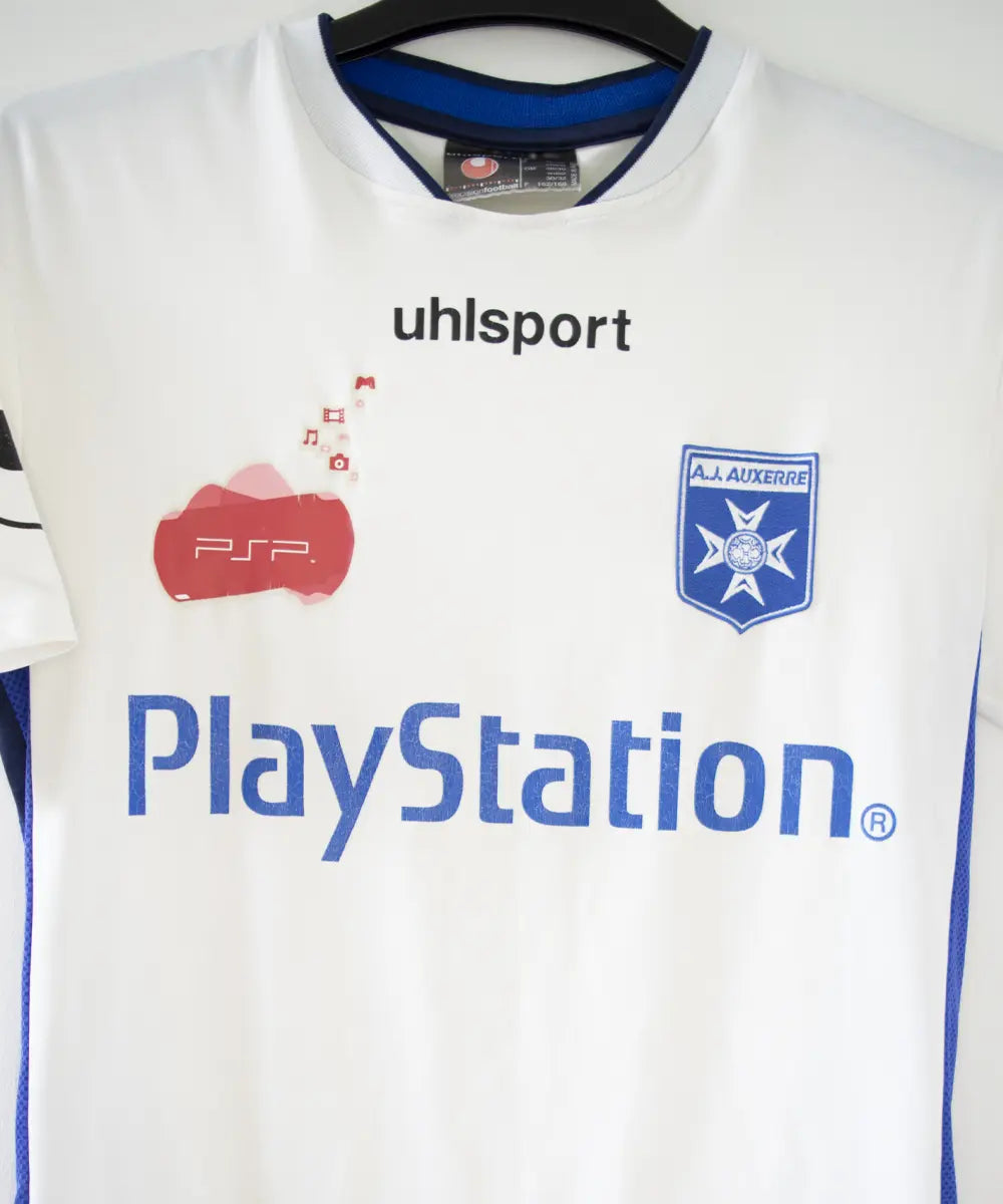 Maillot domicile de l'AJ Auxerre de couleur blanc et bleu. On peut retrouver l'équipementier uhlsport et les sponsors PSP et Playstation