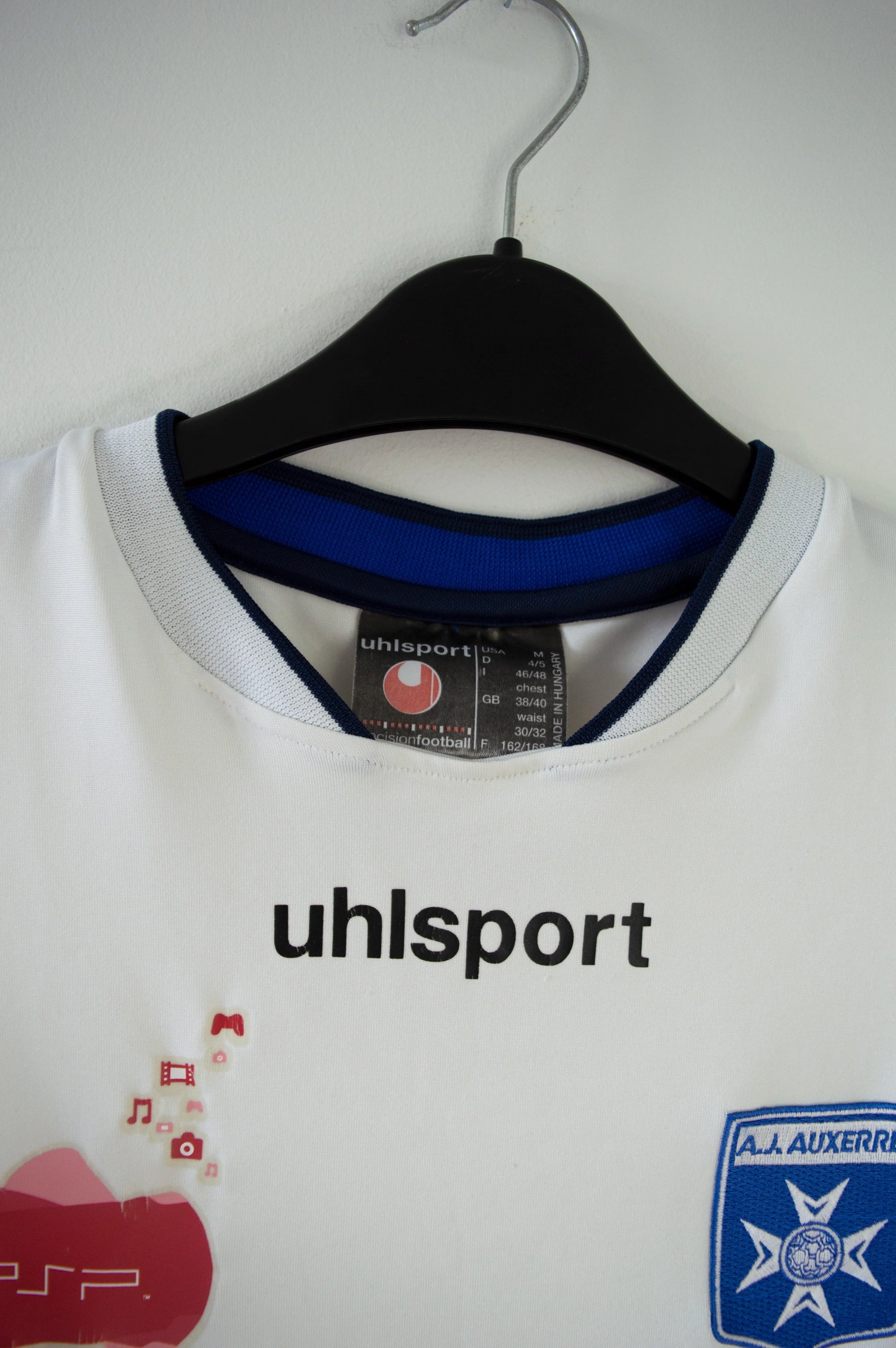 Maillot domicile de l'AJ Auxerre de couleur blanc et bleu. On peut retrouver l'équipementier uhlsport et les sponsors PSP et Playstation