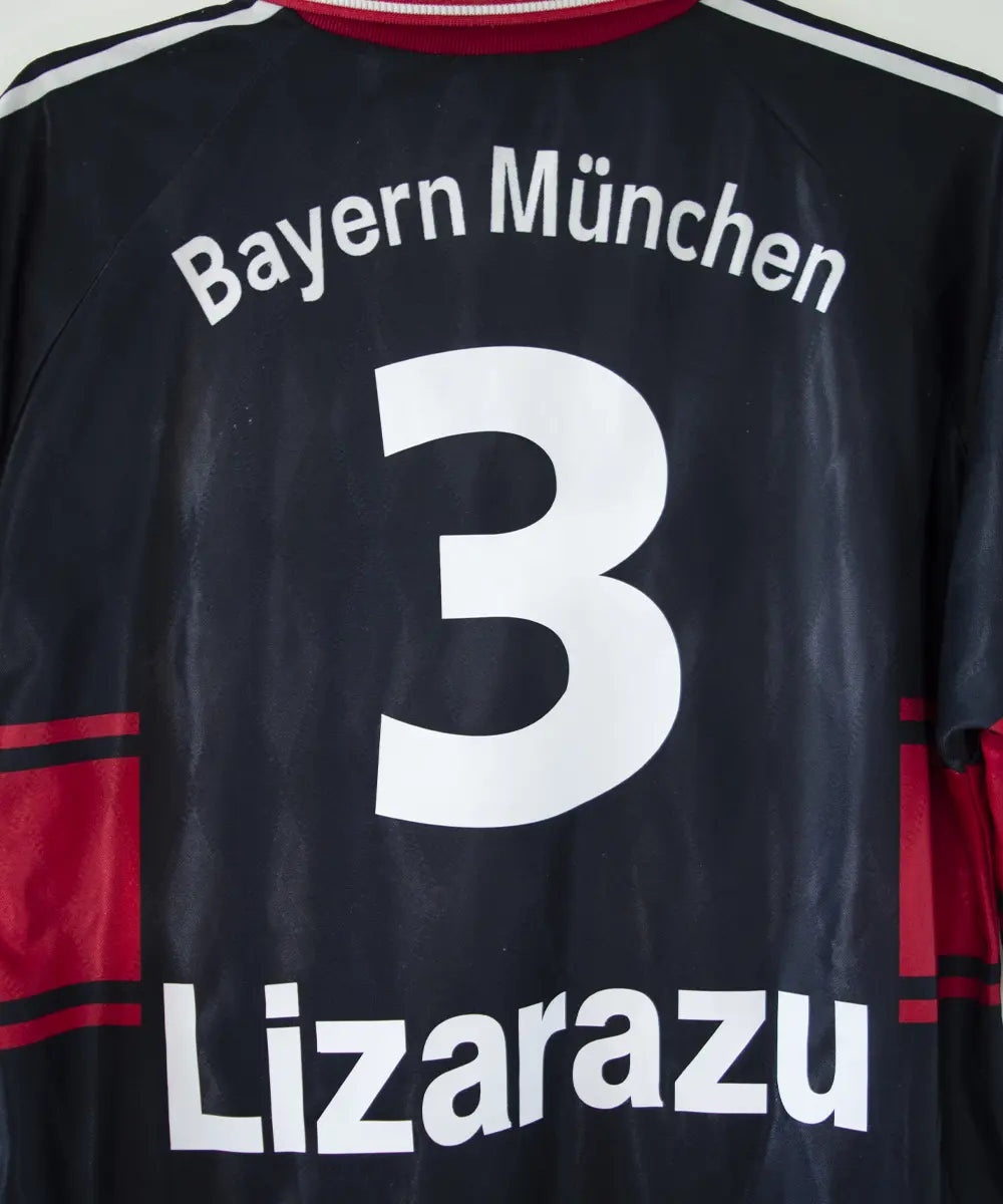 Maillot domicile noir rouge et blanc du bayern munich de la saison 1997-1998. On peut retrouver l'équipementier adidas et le sponsor opel. Le maillot est floqué du numéro 3 Lizarazu