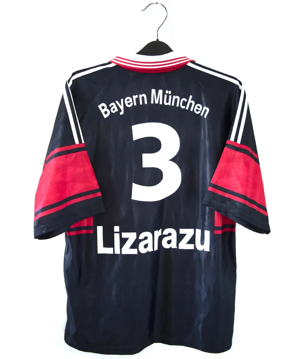 Maillot domicile noir rouge et blanc du bayern munich de la saison 1997-1998. On peut retrouver l'équipementier adidas et le sponsor opel. Le maillot est floqué du numéro 3 Lizarazu