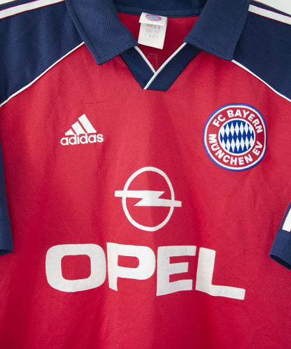Maillot domicile rouge et bleu vintage du bayern munich de la saison 1999-2001. On peut retrouver l'équipementier adidas et le sponsor opel. Le maillot est floqué du numéro 9 Elber