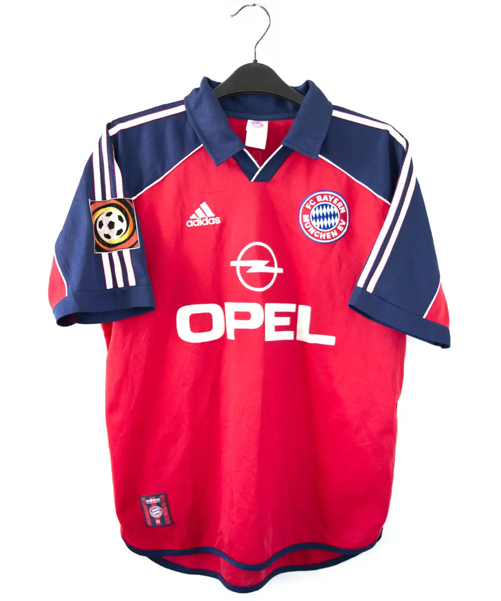 Maillot domicile rouge et bleu vintage du bayern munich de la saison 1999-2001. On peut retrouver l'équipementier adidas et le sponsor opel. Le maillot est floqué du numéro 9 Elber