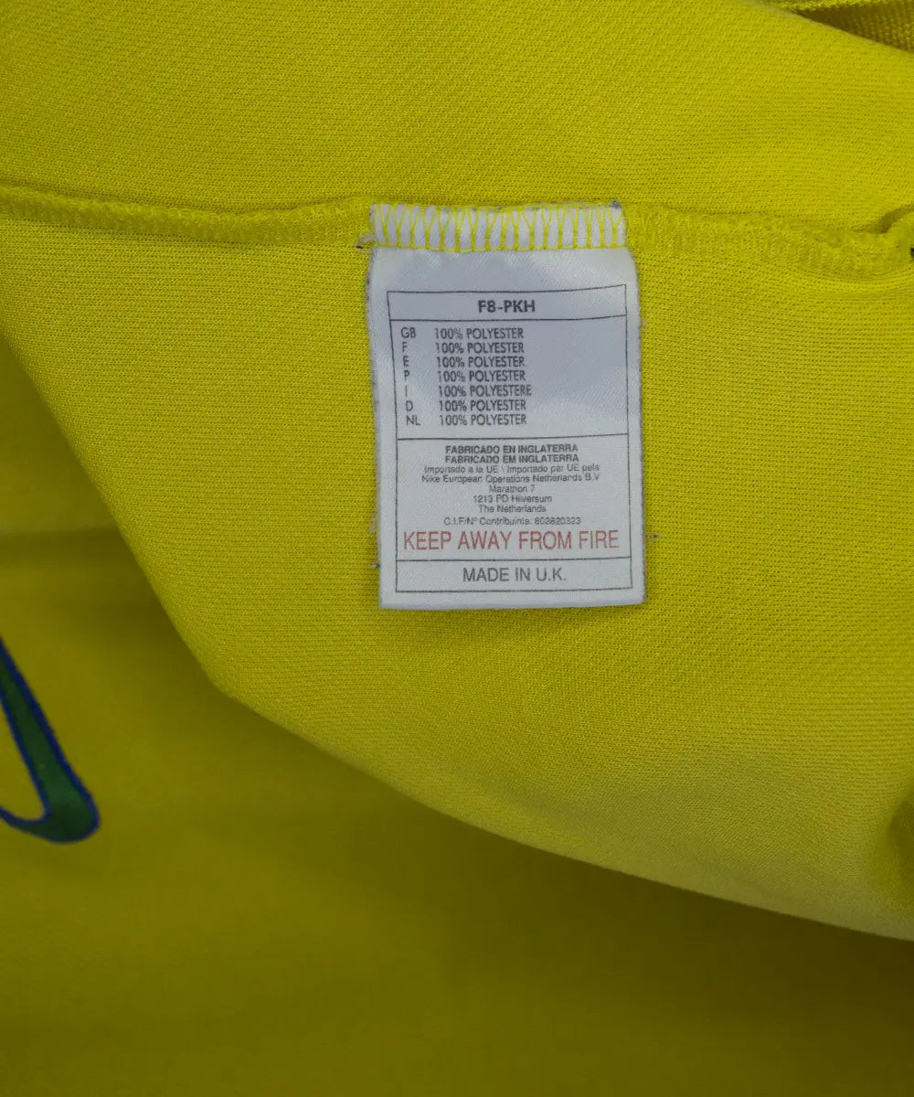 Maillot vintage domicile jaune et vert du bresil lors de la coupe du monde 1998. On peut retrouver l'équipementier nike. On peut voir l'étiquette comportant les numéros F8-PKH