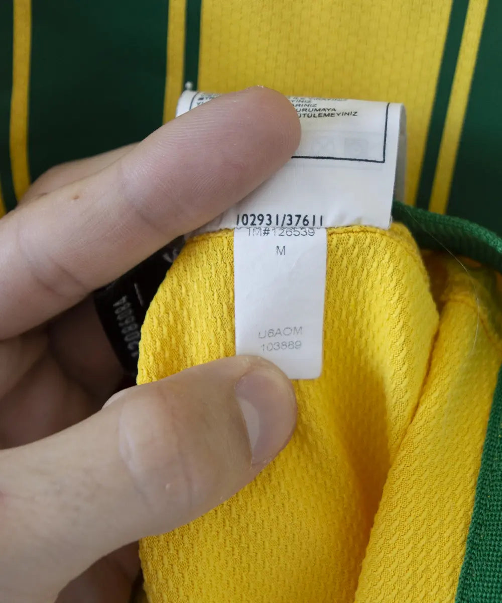 Maillot brésil jaune et vert porté lors de la coupe du monde 2006. On peut retrouver l'équipementier nike. Le maillot est floqué du numéro 9 Ronaldo. Sur cette photo on peut voir l'étiquette d'authenticité comportant les numéros 103889