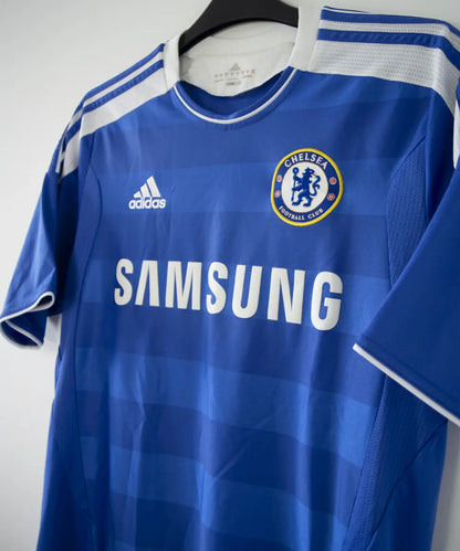 Maillot de foot vintage bleu domicile de chelsea de la saison 2011-2012. On peut retrouver l'équipementier adidas et le sponsor samsung. Le maillot est floqué du numéro 11 Didier Drogba. Le maillot comporte l'étiquette V13927