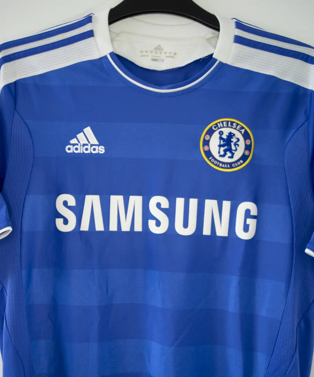 Maillot de foot vintage bleu domicile de chelsea de la saison 2011-2012. On peut retrouver l'équipementier adidas et le sponsor samsung. Le maillot est floqué du numéro 11 Didier Drogba. Le maillot comporte l'étiquette V13927