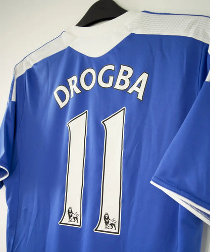 Maillot de foot vintage bleu domicile de chelsea de la saison 2011-2012. On peut retrouver l'équipementier adidas et le sponsor samsung. Le maillot est floqué du numéro 11 Didier Drogba. Le maillot comporte l'étiquette V13927