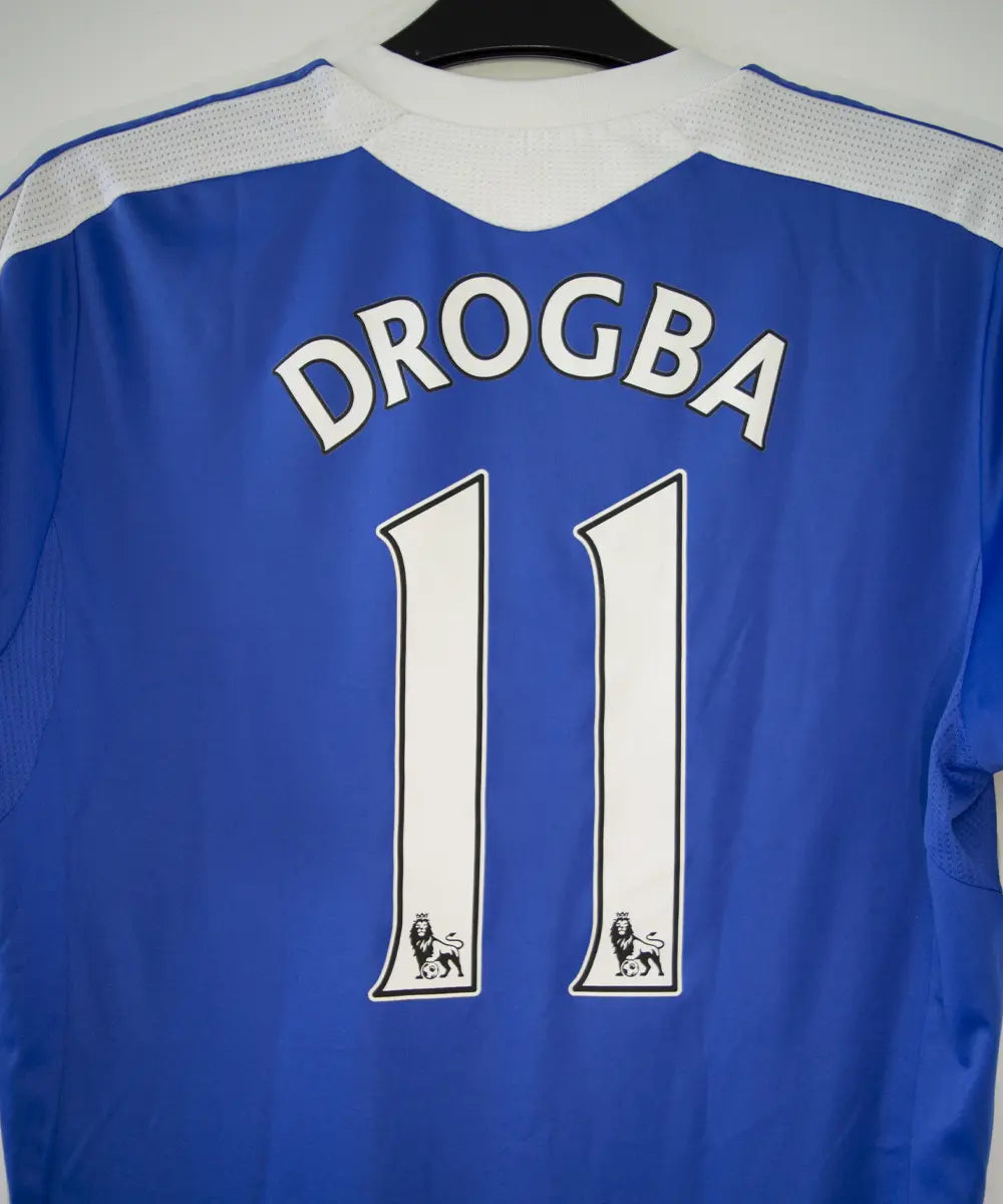 Maillot de foot vintage bleu domicile de chelsea de la saison 2011-2012. On peut retrouver l'équipementier adidas et le sponsor samsung. Le maillot est floqué du numéro 11 Didier Drogba. Le maillot comporte l'étiquette V13927