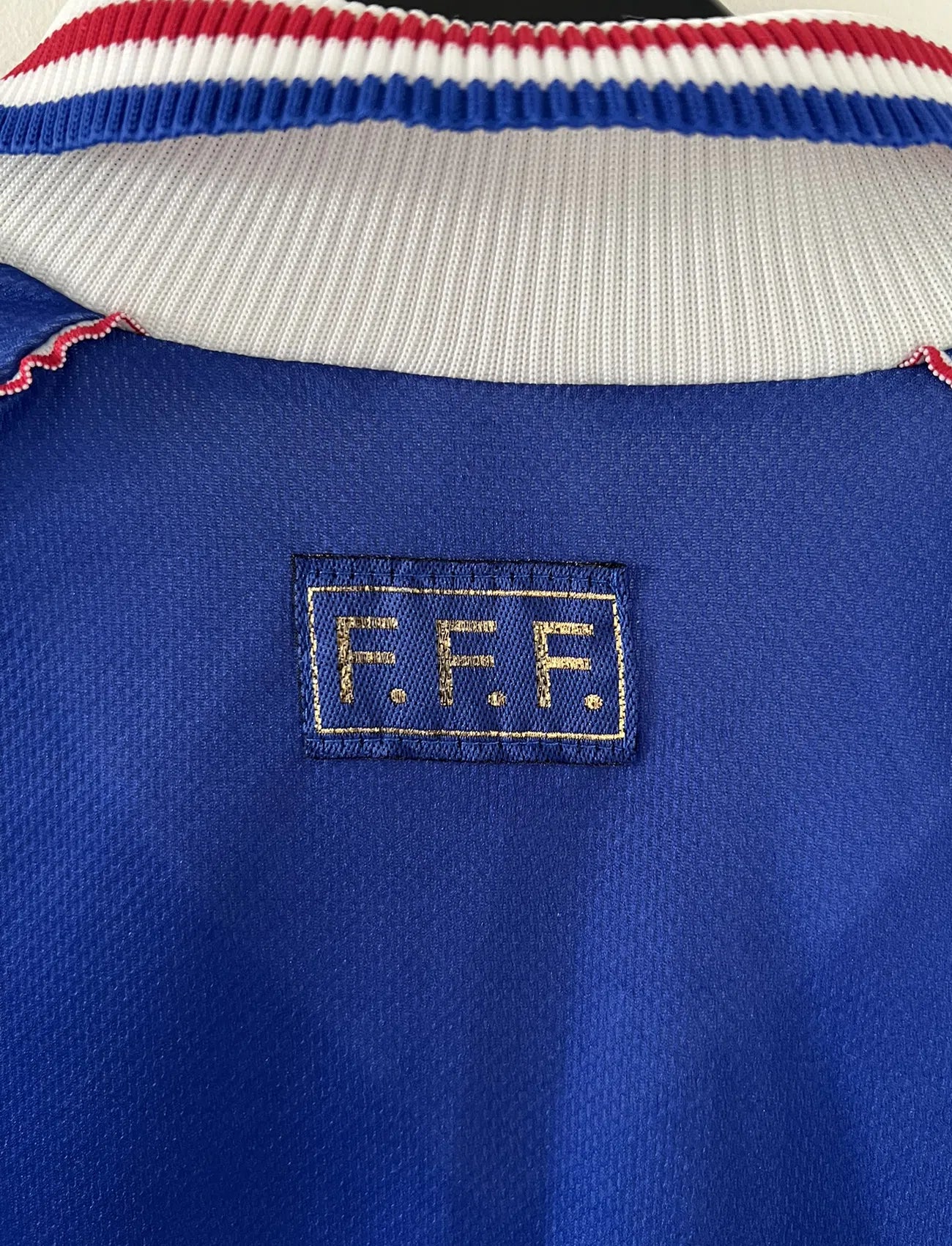 Maillot de foot vintage de l'équipe de france bleu blanc et rouge. Il s'agit du maillot domicile de la coupe du monde 1998. On peut retrouver l'équipementier adidas et le coq avec l'étoile. Le maillot possède la signature pour toi de Didier Deschamps