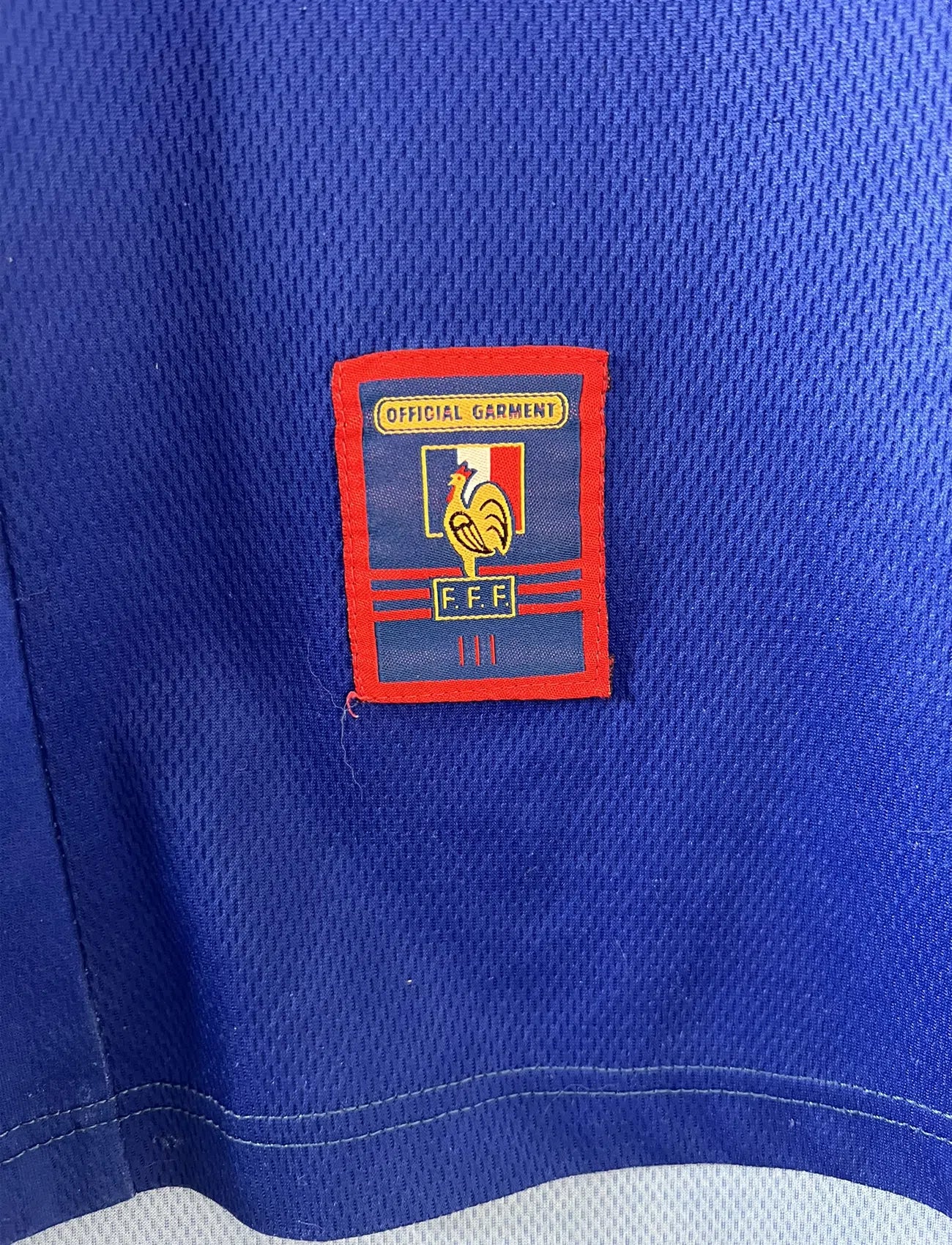 Maillot de foot vintage de l'équipe de france bleu blanc et rouge. Il s'agit du maillot domicile de la coupe du monde 1998. On peut retrouver l'équipementier adidas et le coq sans l'étoile. Le maillot possède la signature pour toi de Zinedine Zidane