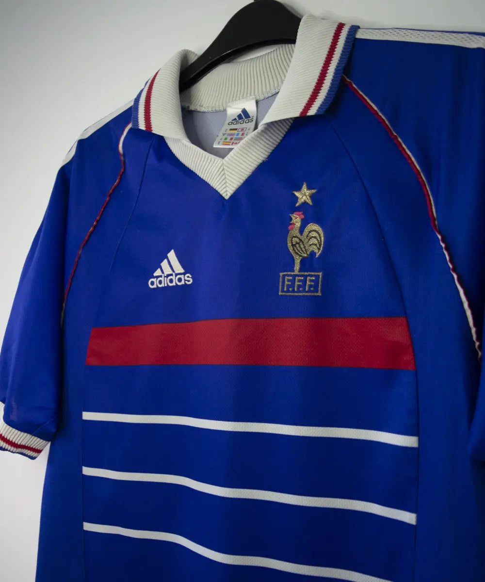 Maillot de foot vintage bleu blanc et rouge de l'équipe de france 1998. On peut retrouver l'équipementier adidas. Le maillot est floqué du numéro 10 Zinedine Zidane