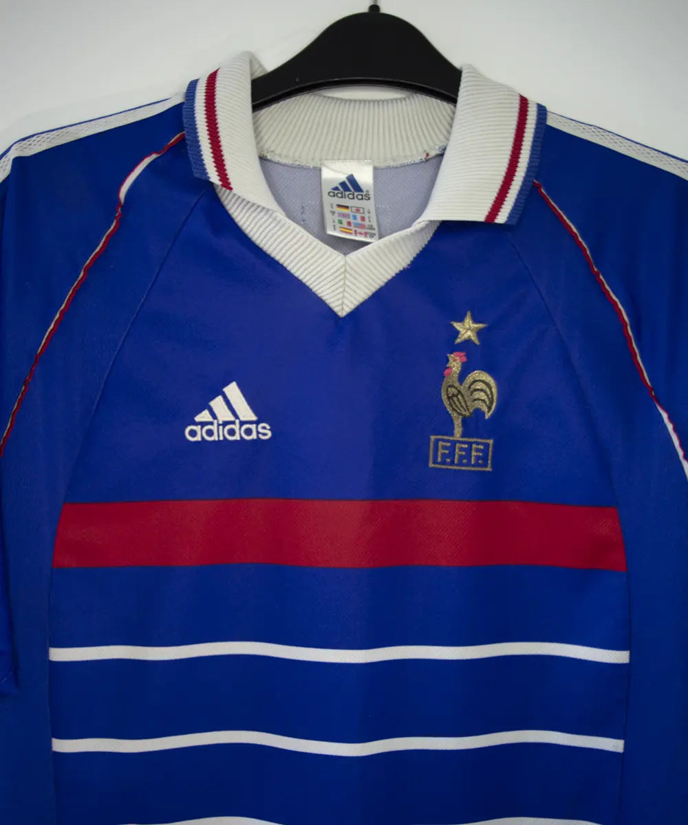 Maillot de foot vintage bleu blanc et rouge de l'équipe de france 1998. On peut retrouver l'équipementier adidas. Le maillot est floqué du numéro 10 Zinedine Zidane