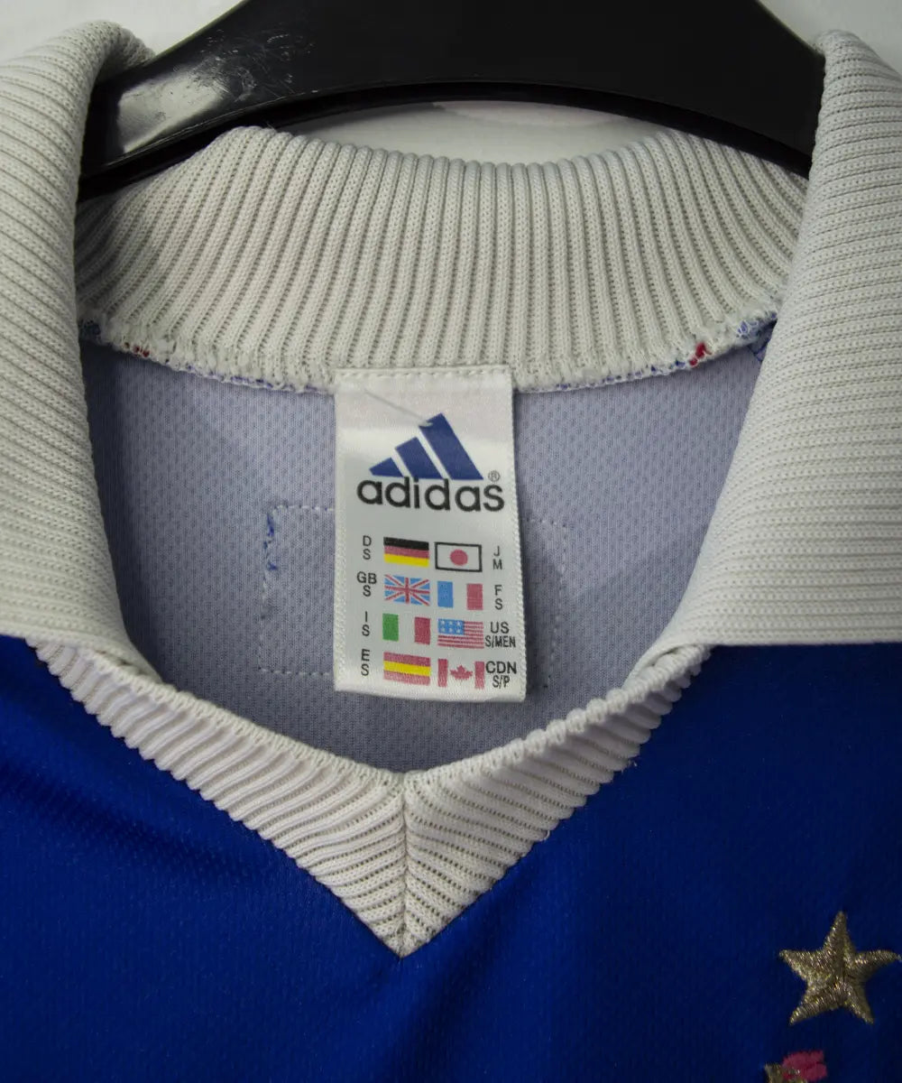 Maillot de foot vintage bleu blanc et rouge de l'équipe de france 1998. On peut retrouver l'équipementier adidas. Le maillot est floqué du numéro 10 Zinedine Zidane