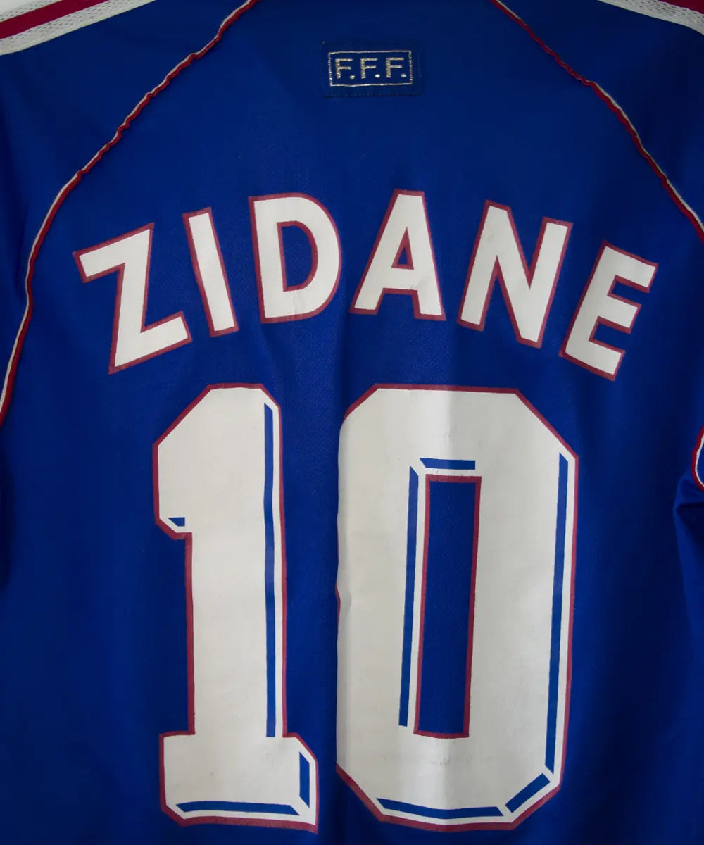 Maillot de foot vintage bleu blanc et rouge de l'équipe de france 1998. On peut retrouver l'équipementier adidas. Le maillot est floqué du numéro 10 Zinedine Zidane