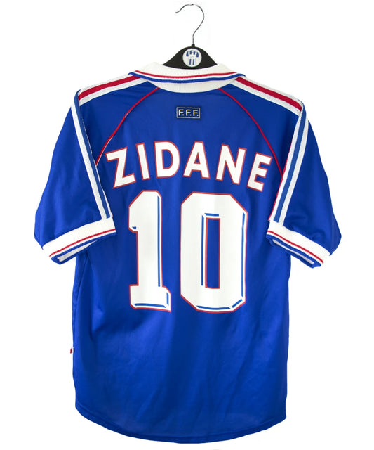 Maillot vintage domicile bleu, blanc et rouge de l'équipe de france 1998. On peut retrouver l'équipementier adidas. Le maillot est floqué du numéro 10 Zinedine Zidane avec le flocage à l'avant et à l'arrière du maillot. Il s'agit d'un maillot authentique d'époque