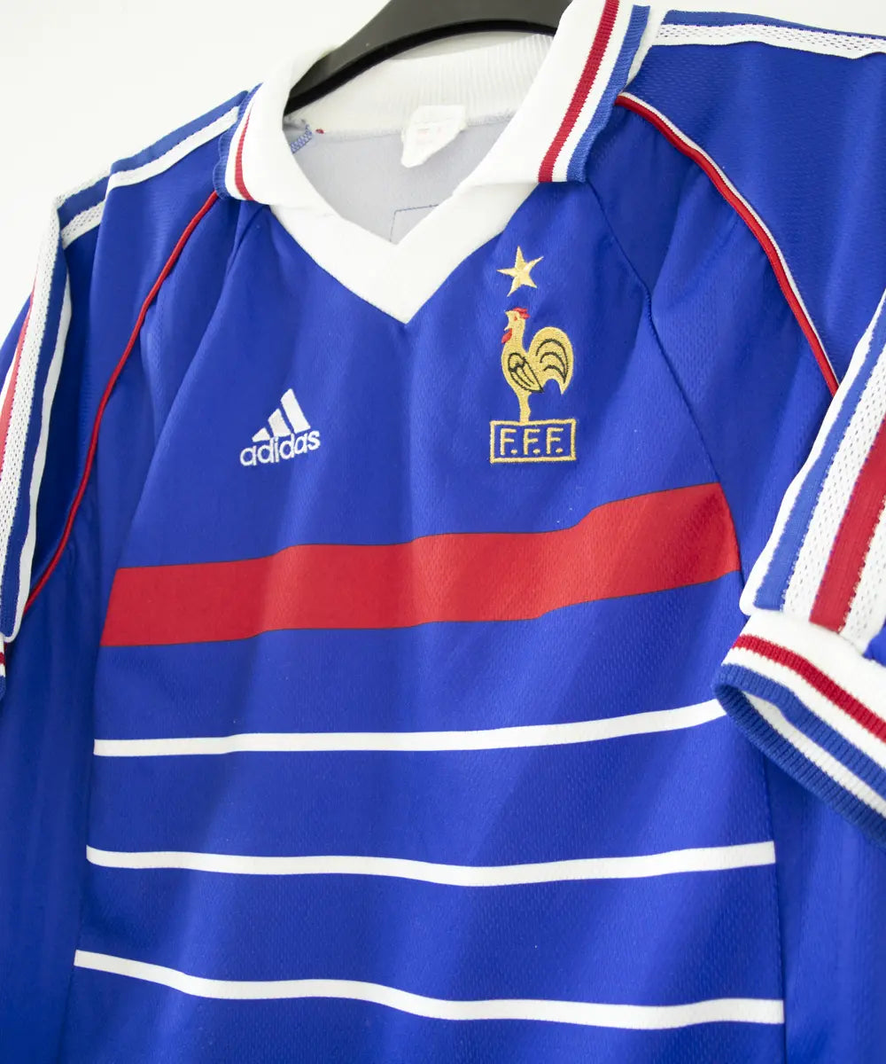 Maillot de foot authentique de l'équipe de france 1998. Le maillot est floqué du numéro 10 Zinedine Zidane. Sur cette photo on peut voir le devant du maillot de côté