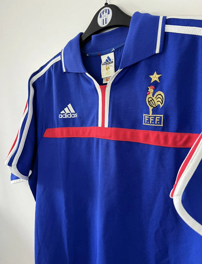 Maillot de foot vintage domicile de l'équipe de france 2000. Le maillot est de couleur bleu blanc et rouge. On peut retrouver l'équipementier adidas. Il s'agit d'un maillot authentique comportant les numéros 647194.
