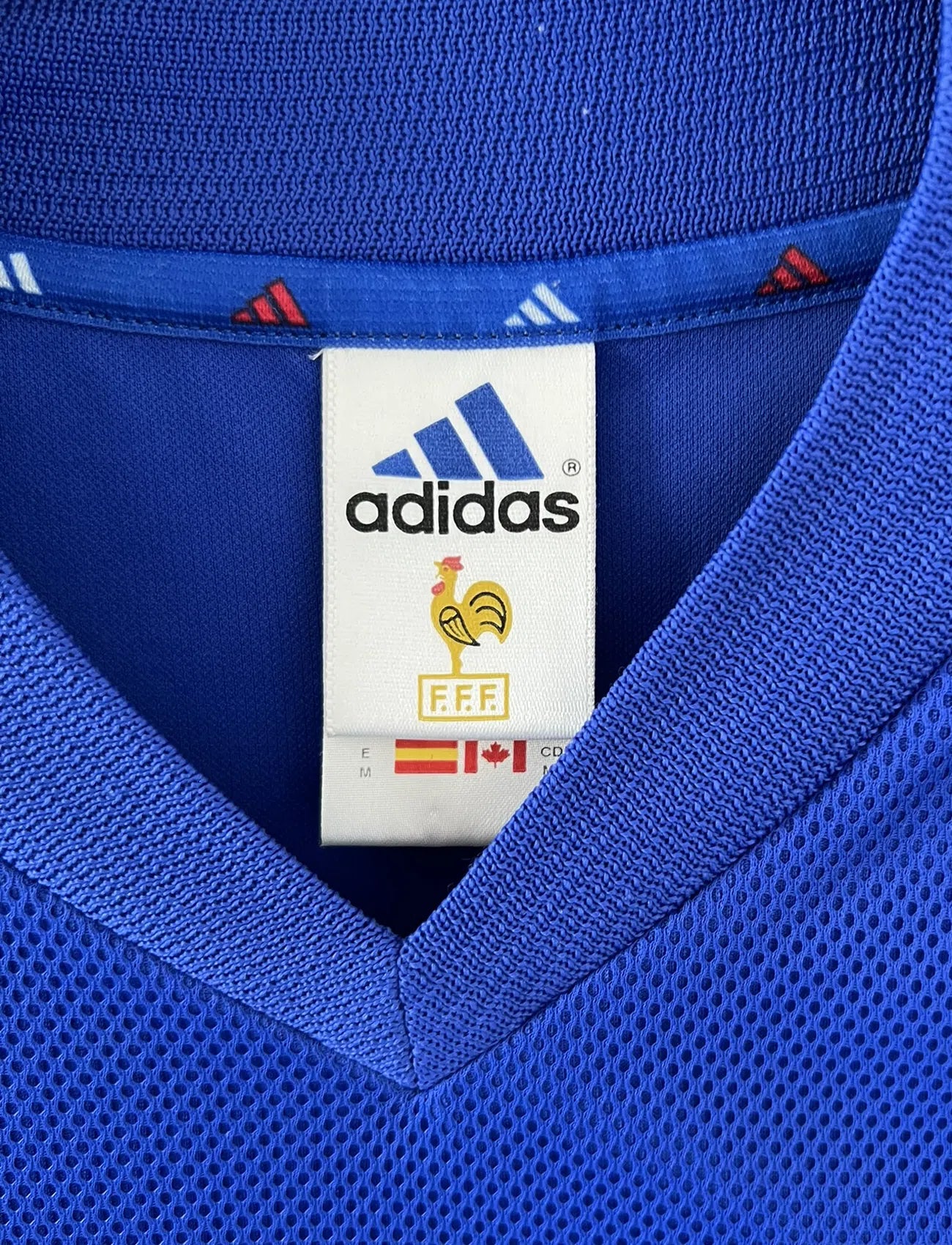 Maillot de foot vintage domicile de l'Equipe de France 2002. Le maillot est de couleur bleu, blanc et rouge. On peut retrouver l'équipementier adidas et le flocage de Zinedine Zidane. Il s'agit d'un maillot authentique. Le maillot possède l'étiquette d'authenticité comportant les numéros 139531.