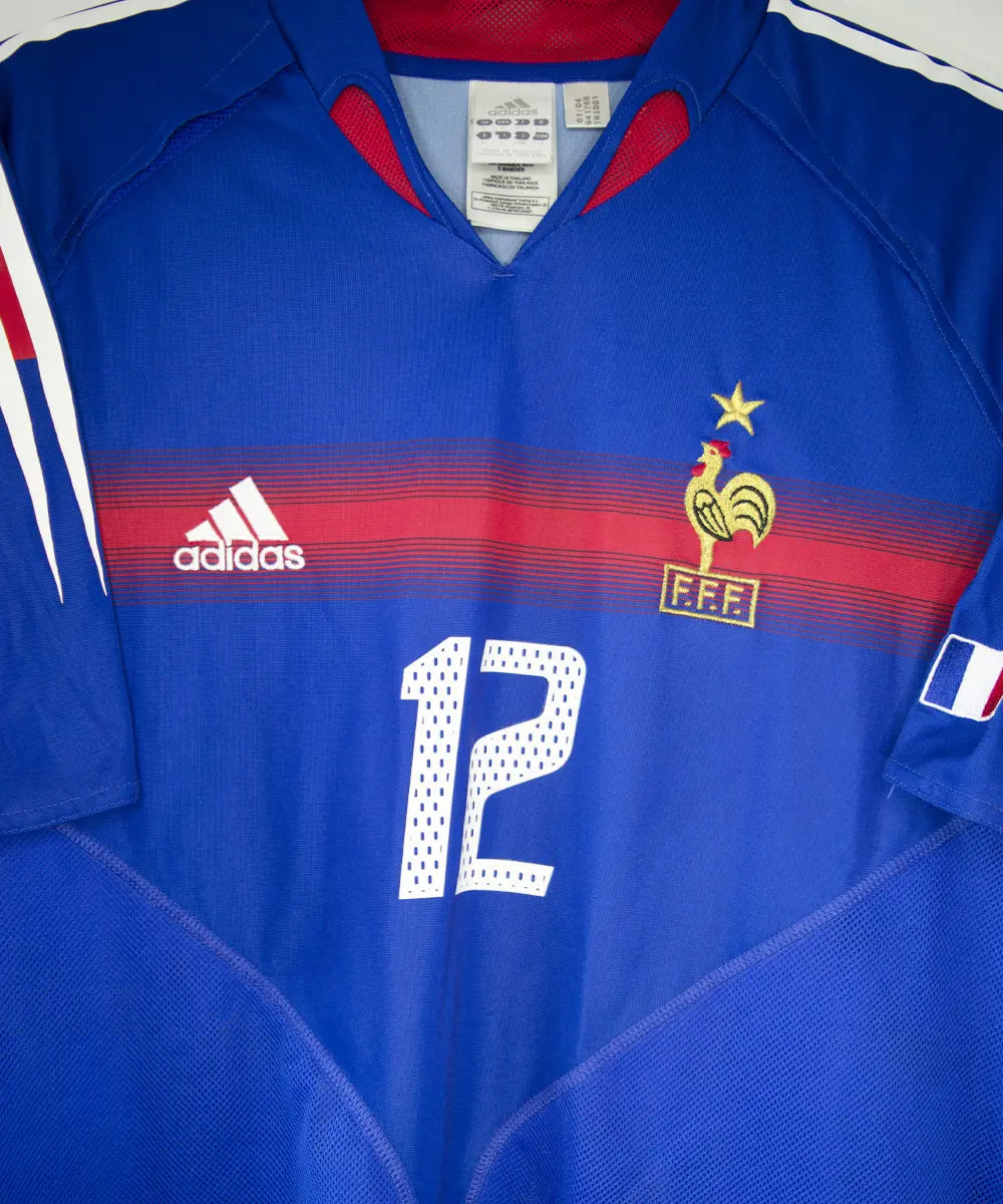 Maillot domicile bleu, blanc et rouge de l'équipe de france 2004-2006. On peut retrouver l'équipementier adidas. Le maillot est floqué du numéro 12 Thierry Henry