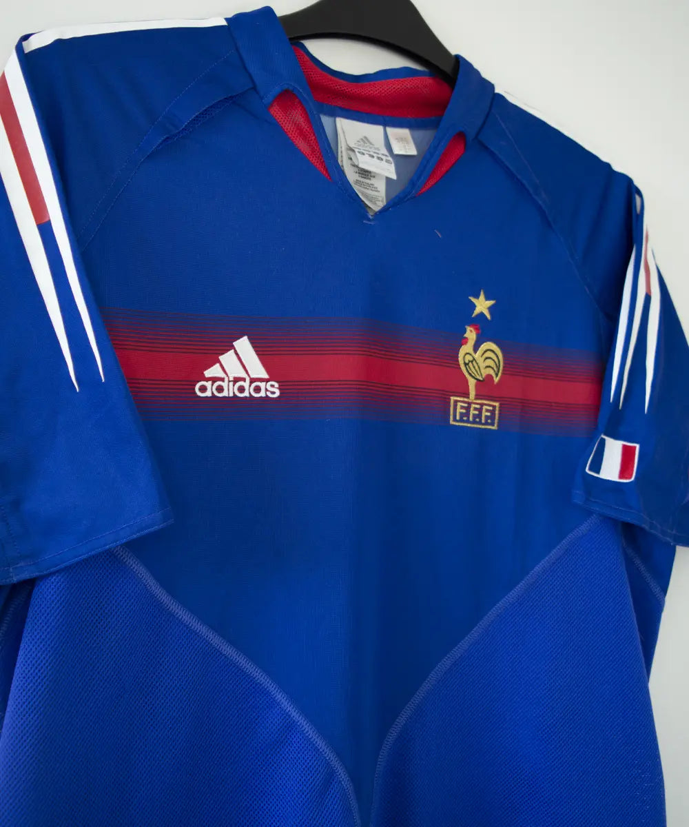 Maillot domicile de l'équipe de france 2004 2006 de couleur bleu blanc et rouge. On peut retrouver l'équipementier adidas. Le maillot est floqué du numéro 10 Zidane