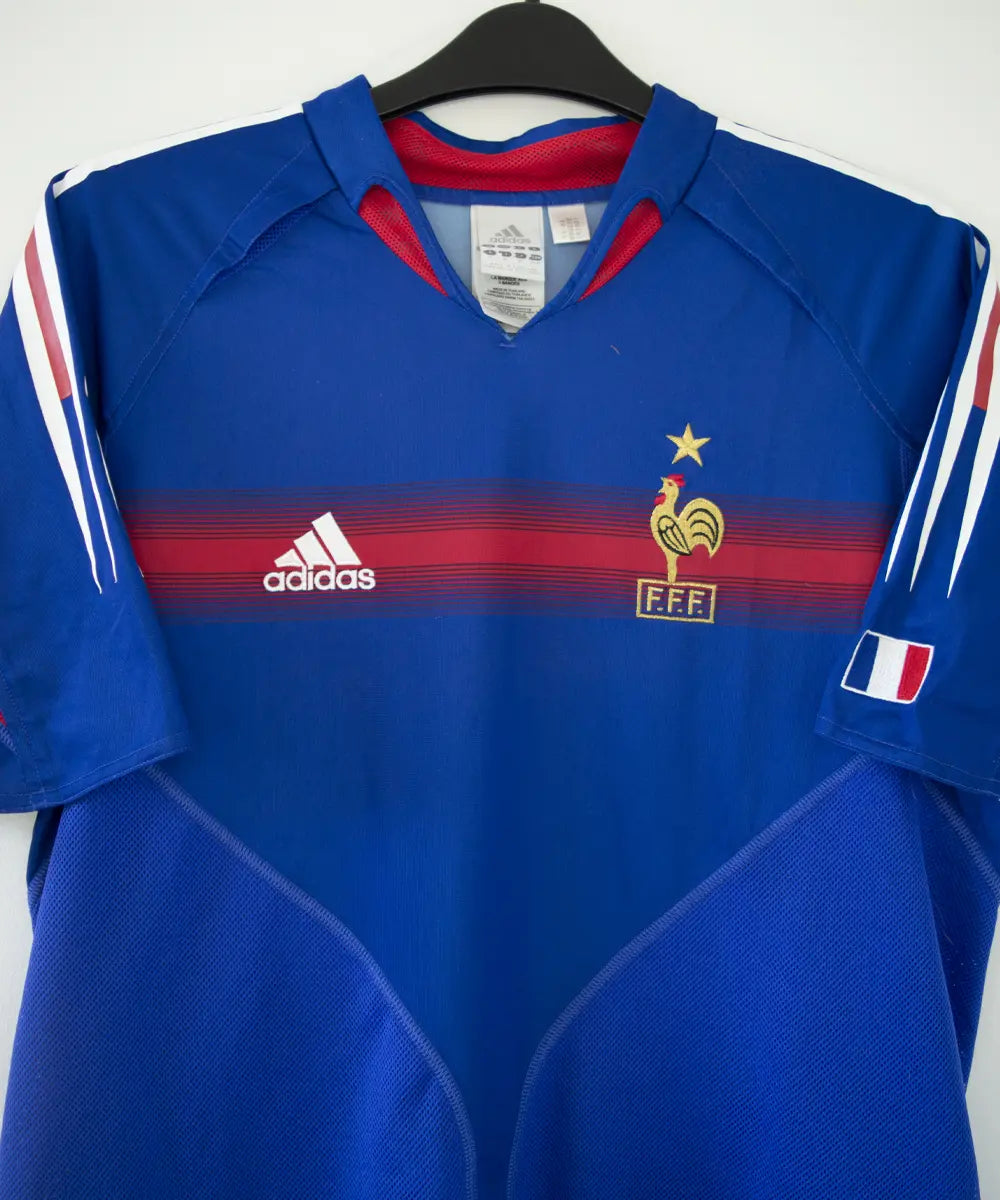 Maillot domicile de l'équipe de france 2004 2006 de couleur bleu blanc et rouge. On peut retrouver l'équipementier adidas. Le maillot est floqué du numéro 10 Zidane