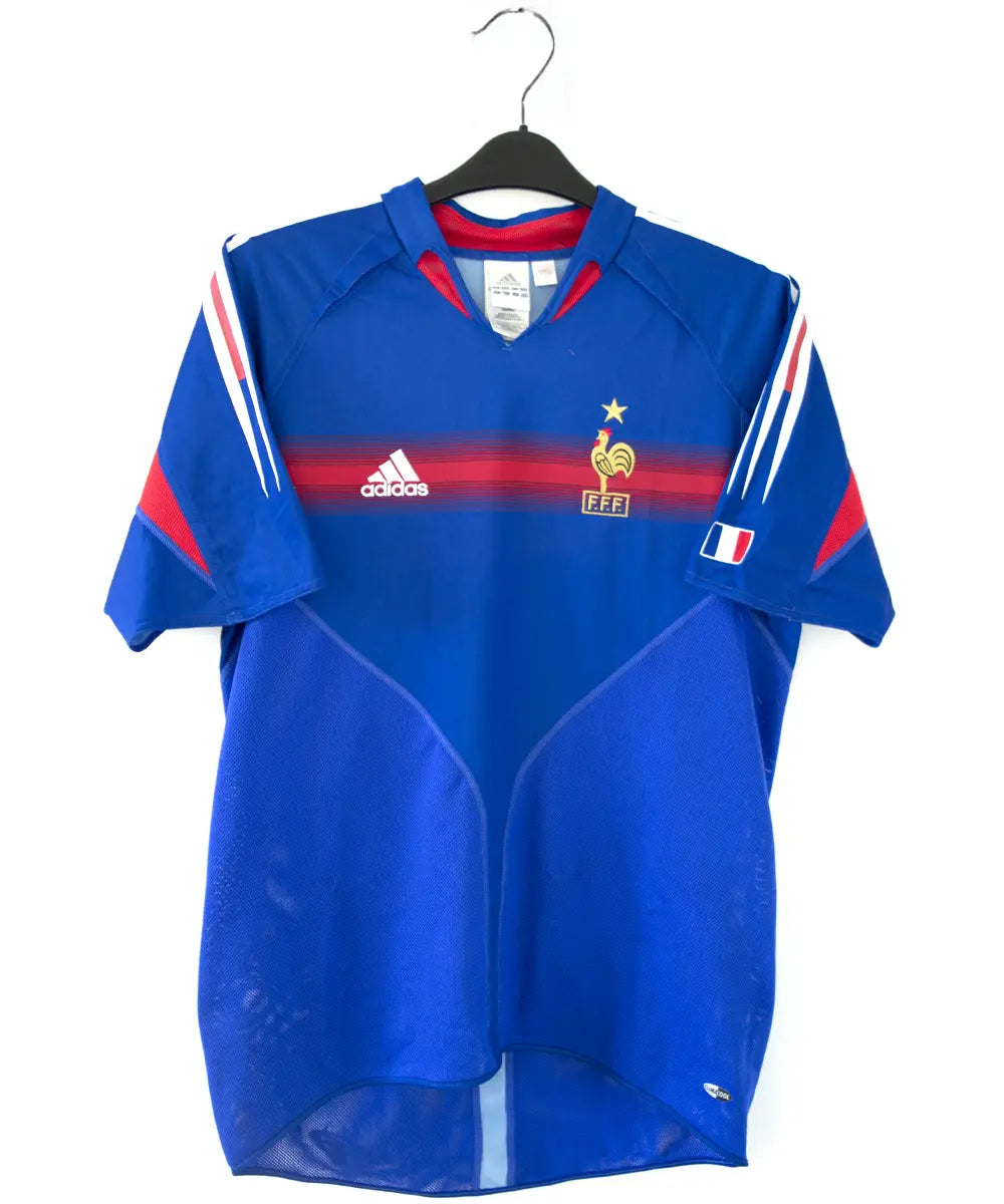 Maillot domicile de l'équipe de france 2004 2006 de couleur bleu blanc et rouge. On peut retrouver l'équipementier adidas. Le maillot est floqué du numéro 10 Zidane