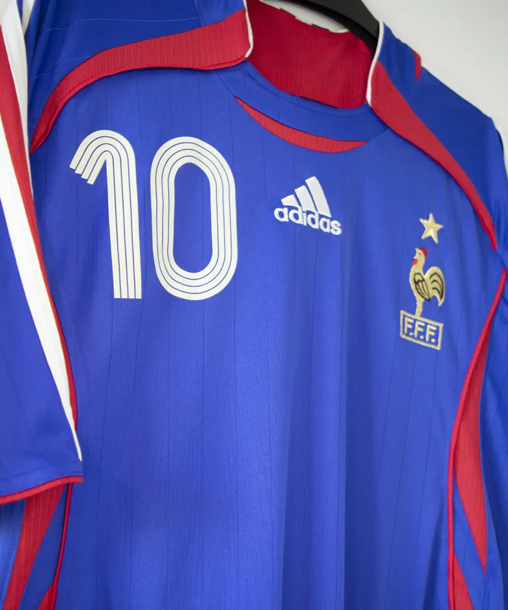 Maillot domicile de l'équipe de france porté lors de la coupe du monde 2006. Le maillot est de couleur bleu blanc et rouge. On peut retrouver l'équipementier adidas. Le maillot est floqué du numéro 10 Zinedine Zidane. Sur cette photo on peut apercevoir le maillot de côté