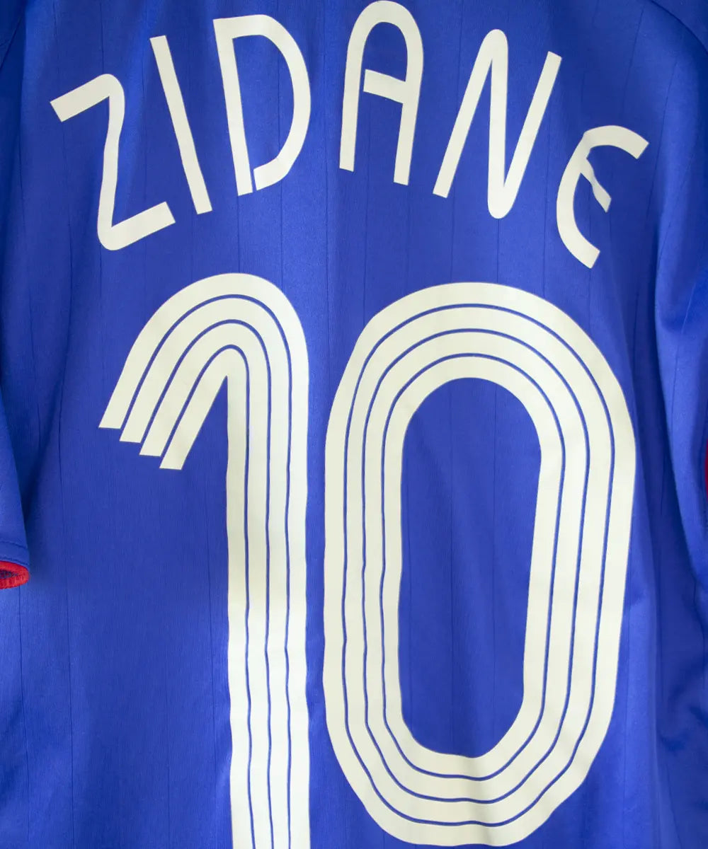 Maillot domicile de l'équipe de france porté lors de la coupe du monde 2006. Le maillot est de couleur bleu blanc et rouge. On peut retrouver l'équipementier adidas. Le maillot est floqué du numéro 10 Zinedine Zidane. Sur cette photo on peut apercevoir le flocage de près