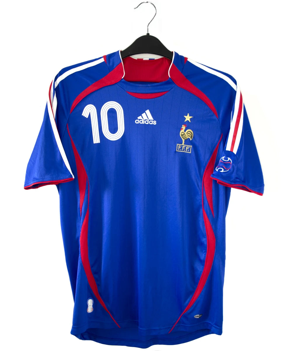 Maillot de foot vintage domicile bleu, blanc et rouge de l'équipe de france 2006. On peut retrouver l'équipementier adidas. Le maillot est floqué du numéro 10 Zinedine Zidane. Il s'agit d'un maillot authentique