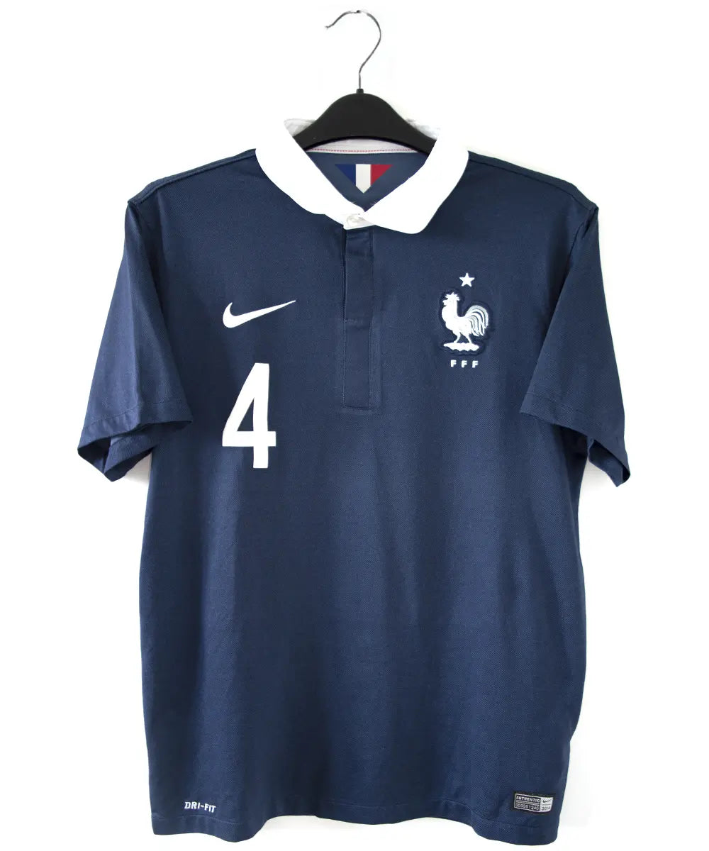 Maillot domicile équipe de france édité lors de la coupe du monde 2014. Le maillot est de couleur bleu et blanc. On peut retrouver l'équipementier nike. Le maillot est floqué du numéro 4 Varane. Sur cette photo on peut voir le devant du maillot.