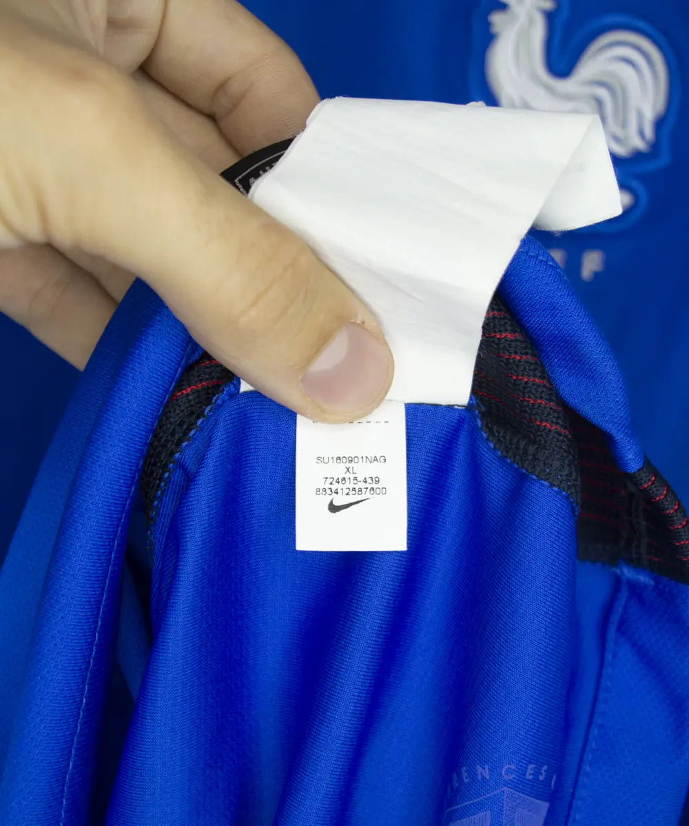Maillot de foot domicile de l'équipe de france 2016. On peut retrouver l'équipementier nike. Le maillot est de couleur bleu. Le maillot est floqué du numéro 7 Antoine Griezmann. On peut voir sur cette photo l'étiquette du maillot qui comporte les numéros 724615-439