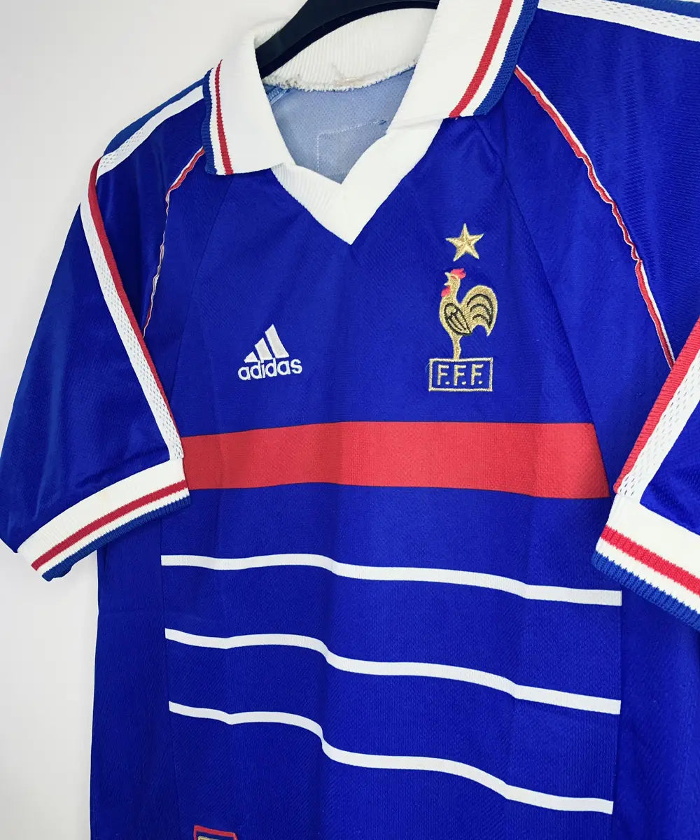 Maillot vintage domicile bleu, blanc et rouge de l'Equipe de France 1998. On peut retrouver l'équipementier adidas