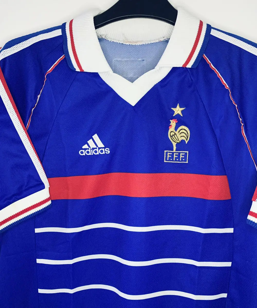 Maillot vintage domicile bleu, blanc et rouge de l'Equipe de France 1998. On peut retrouver l'équipementier adidas