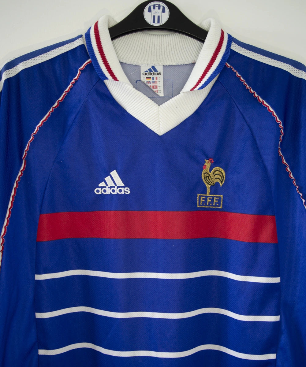 Maillot de foot vintage bleu, blanc et rouge de l'équipe de france 1998. On peut retrouver l'équipementier adidas. Il s'agit d'un maillot authentique édité avant la finale de la coupe du monde car celui-ci ne possède pas l'étoile.