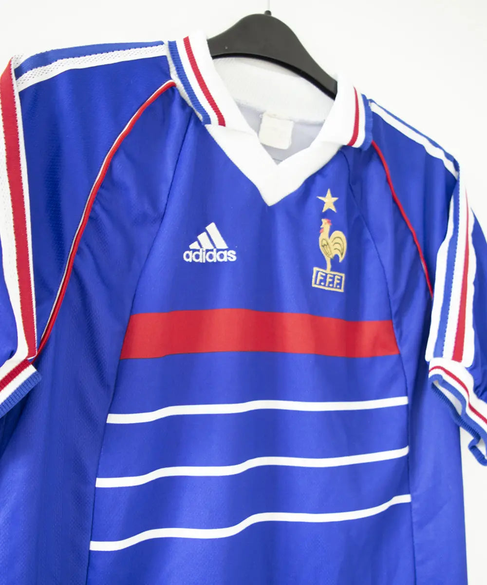 Maillot domicile bleu adidas de l'équipe de france 1998. Le maillot est floqué du numéro 10 Zinedine Zidane. Sur cette photo on peut voir le devant du maillot de côté