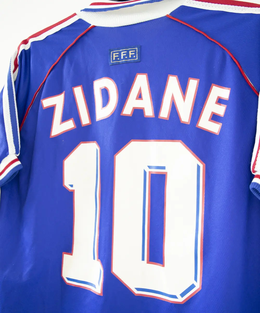 Maillot domicile bleu adidas de l'équipe de france 1998. Le maillot est floqué du numéro 10 Zinedine Zidane. Sur cette photo on peut voir le flocage de côté