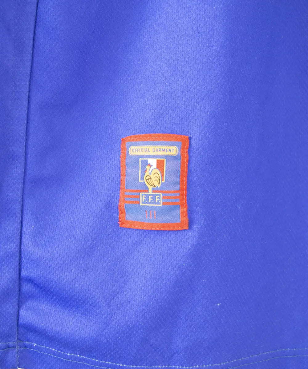 Maillot domicile bleu adidas de l'équipe de france 1998. Le maillot est floqué du numéro 10 Zinedine Zidane. Sur cette photo on peut voir le patch official garment