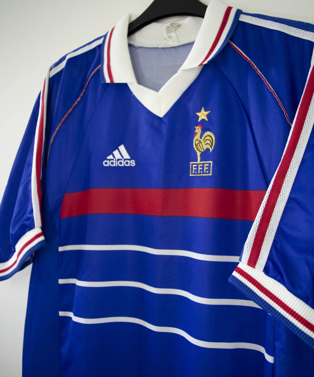 Maillot de foot vintage domicile bleu, blanc et rouge de l'équipe de france 1998. On peut voir l'équipementier adidas. Le maillot est floqué du numéro 10 Zidane. Il s'agit d'un maillot authentique d'époque