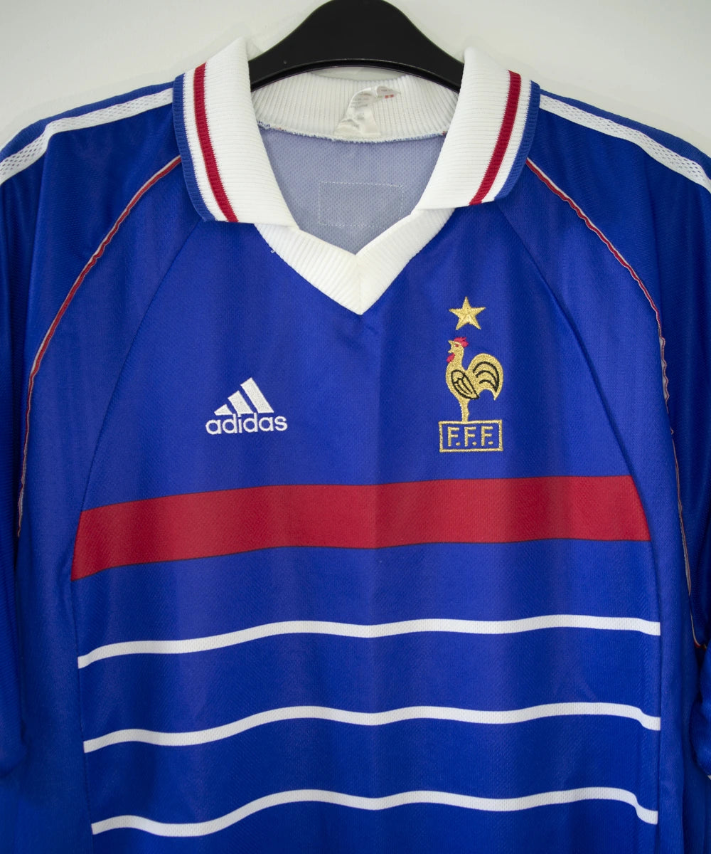 Maillot de foot vintage domicile bleu, blanc et rouge de l'équipe de france 1998. On peut voir l'équipementier adidas. Le maillot est floqué du numéro 10 Zidane. Il s'agit d'un maillot authentique d'époque