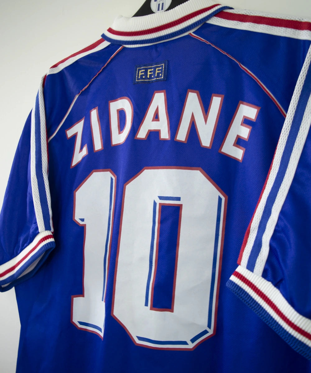 Maillot de foot vintage domicile bleu, blanc et rouge de l'équipe de france 1998. On peut voir l'équipementier adidas. Le maillot est floqué du numéro 10 Zidane. Il s'agit d'un maillot authentique d'époque