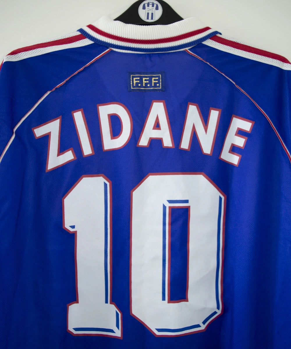 Maillot de foot vintage domicile bleu, blanc et rouge de l'équipe de france 1998. On peut voir l'équipementier adidas. Le maillot est floqué du numéro 10 Zidane. Il s'agit d'un maillot authentique d'époque