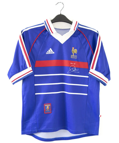Maillot de foot de l'équipe de france 1998. Le maillot est de couleur bleu, blanc rouge. On peut retrouver l'équipementier adidas et la signature de zinedine zidane