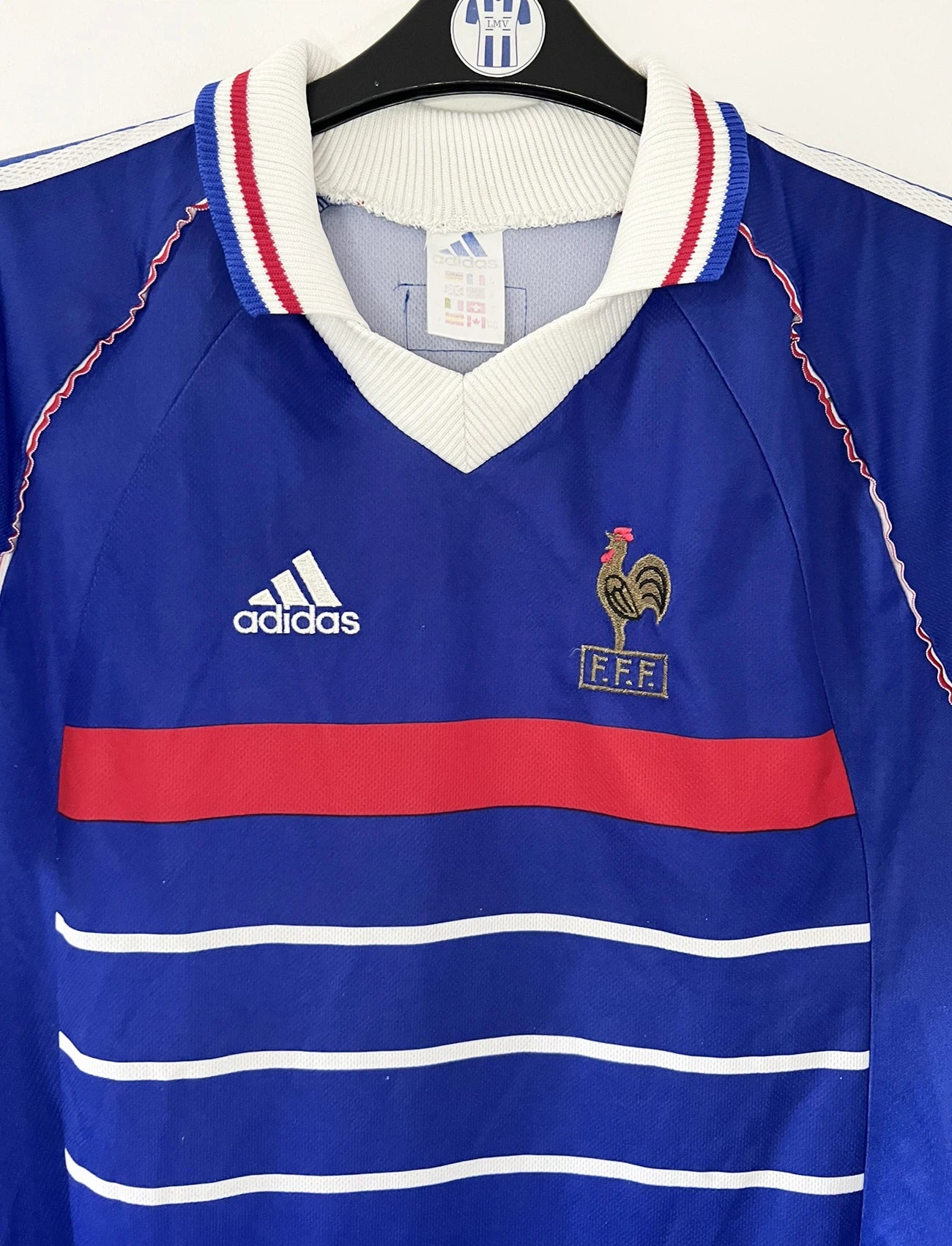 Maillot de foot vintage bleu, blanc et rouge de l'équipe de france 1998. On peut retrouver l'équipementier adidas. Il s'agit d'un maillot authentique édité avant la finale de la coupe du monde car celui-ci ne possède pas l'étoile. Le maillot est floqué du numéro 10 Zidane
