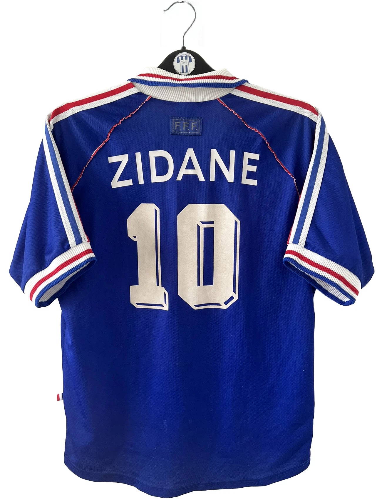 Maillot de foot vintage bleu, blanc et rouge de l'équipe de france 1998. On peut retrouver l'équipementier adidas. Il s'agit d'un maillot authentique édité avant la finale de la coupe du monde car celui-ci ne possède pas l'étoile. Le maillot est floqué du numéro 10 Zidane