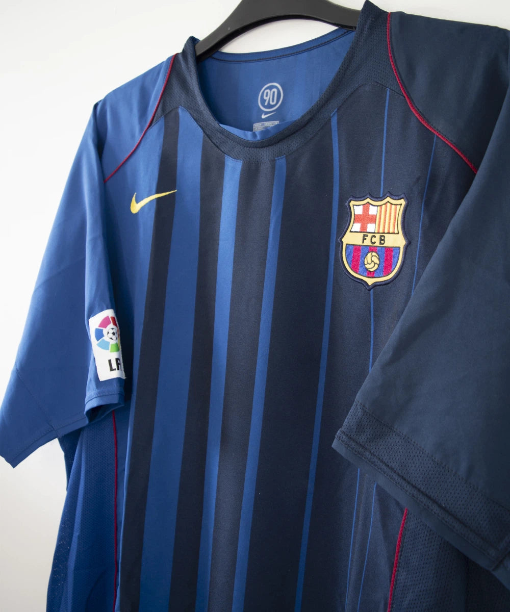 Maillot de foot vintage bleu du FC Barcelone de la saison 2004/2005. On peut retrouver l'équipementier nike. Le maillot est floqué du numéro 9 Samuel Eto'o. On peut voir également sur le maillot la signature de Eto'o. Il s'agit d'un maillot authentique