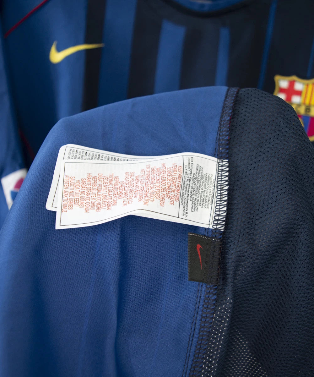 Maillot de foot vintage bleu du FC Barcelone de la saison 2004/2005. On peut retrouver l'équipementier nike. Le maillot est floqué du numéro 9 Samuel Eto'o. On peut voir également sur le maillot la signature de Eto'o. Il s'agit d'un maillot authentique. Sur cette photo on peut voir l'étiquette d'authenticité nike.