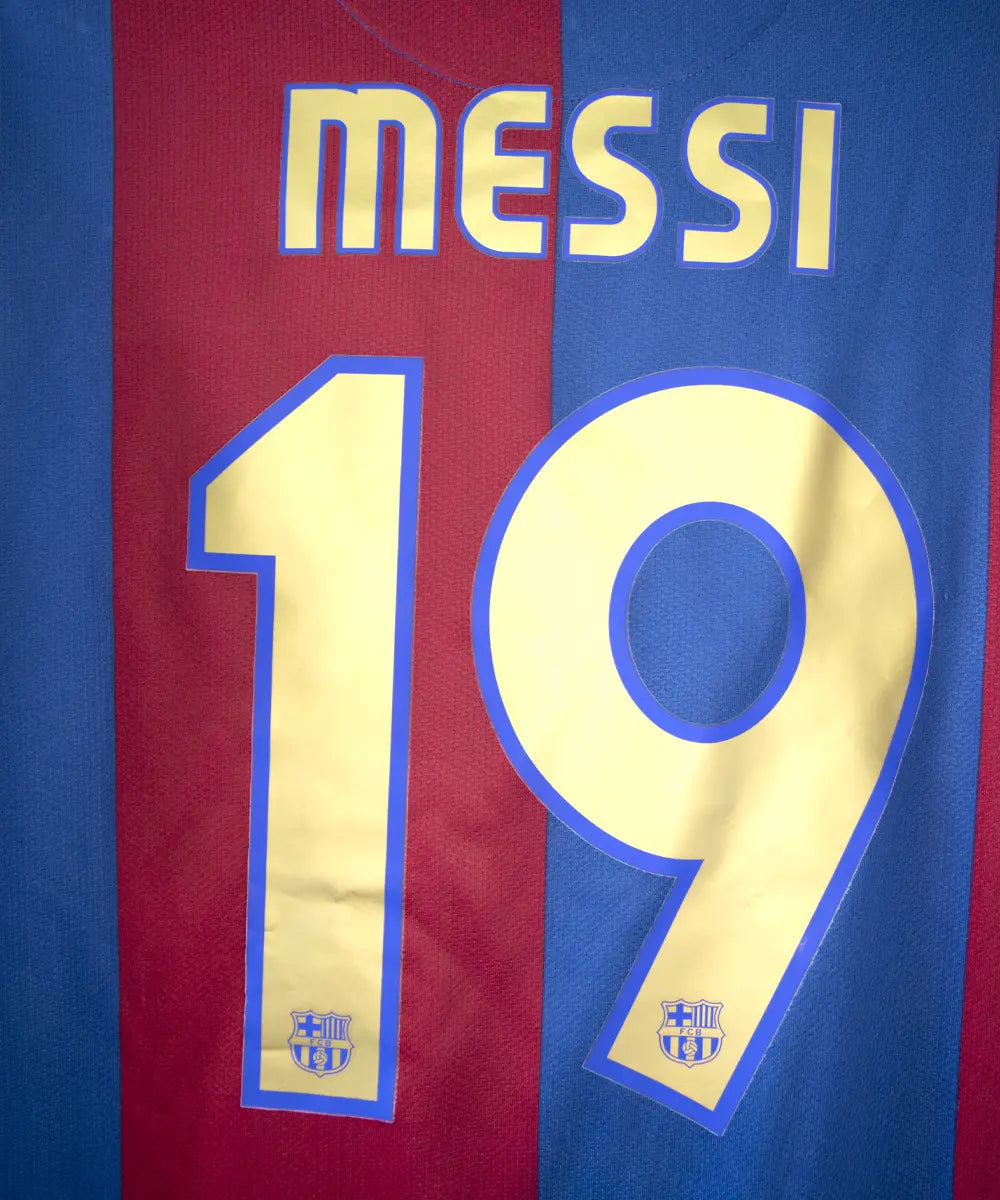 Maillot domicile du FC Barcelone de la saison 2006/2007 rouge et bleu. Le maillot est floqué du numéro 19 Messi. On peut retrouver l'équipementier nike sur le maillot. Sur ce maillot on peut apercevoir le flocage de près